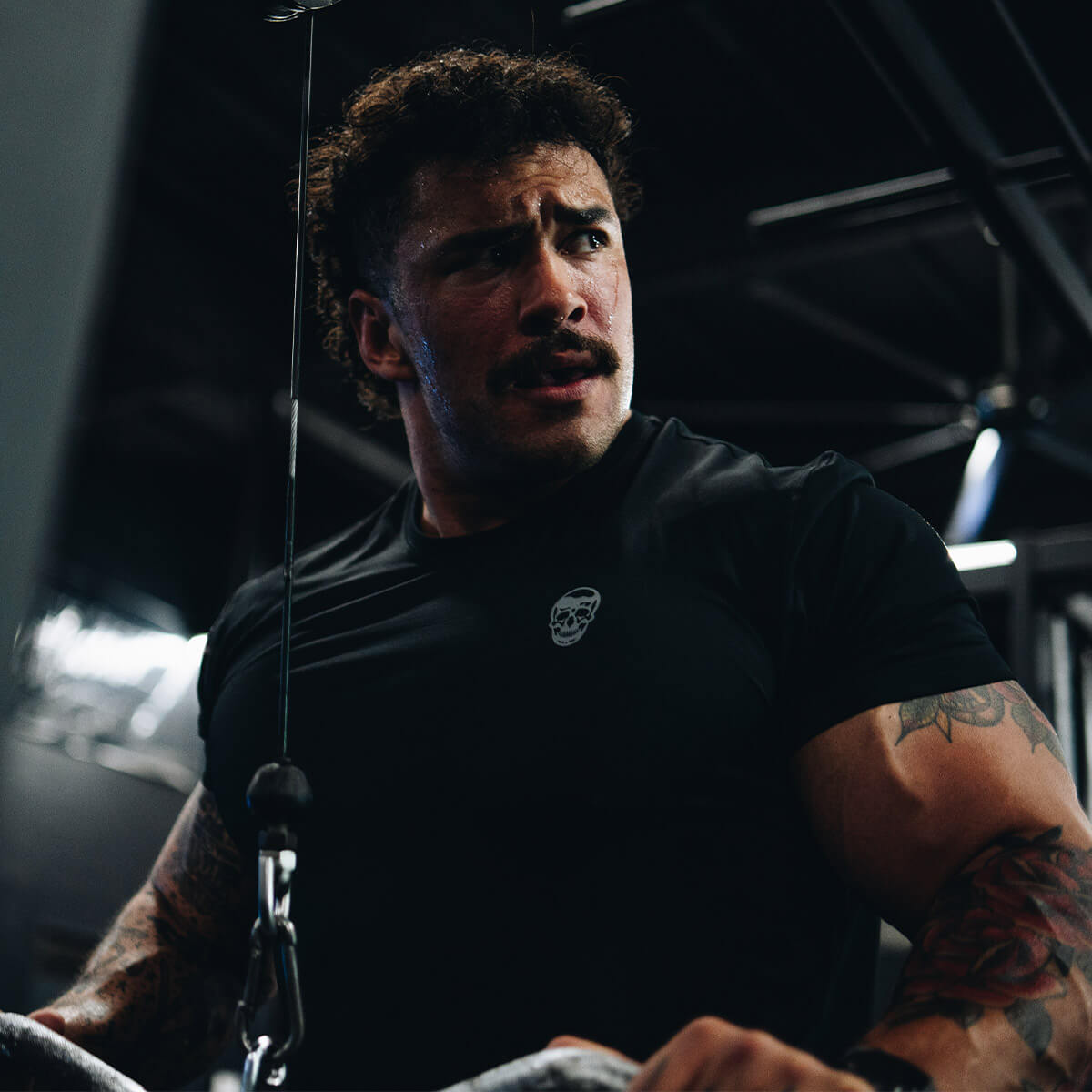 Jack West performs cable triceps extensions in the gym while wearing a Gymreapers performance short sleeve shirt.