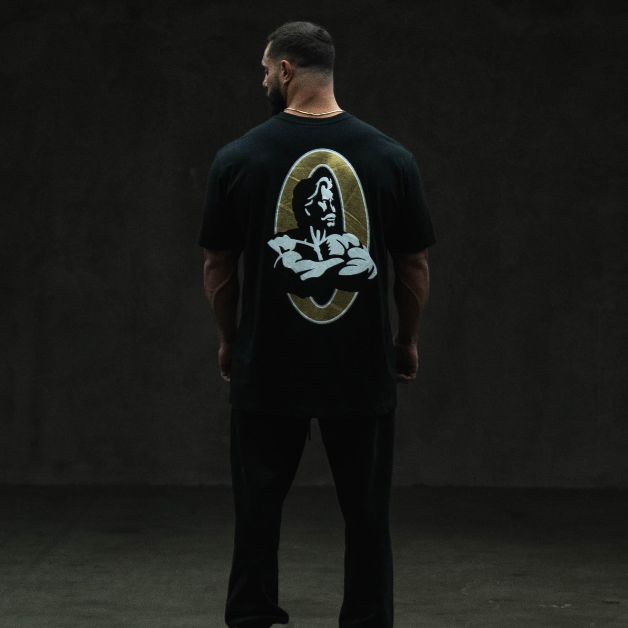 full body shot of athlete wearing the gold olympia basic tee showing back graphic